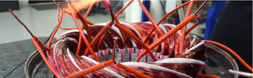 Avvolgimento in rame di uno statore di motore elettrico con cavi di uscita, in officina a Brescia